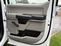 Interior door panel of a 2022 Ford F-550 featuring a handle and control lever with a textured surface and storage compartment