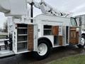 A white 2005 Freightliner M2 106 utility truck with a bucket lift on top and multiple wooden door compartments on the side