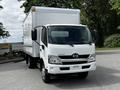 A 2018 Hino 195 truck with a white box truck body and a black grille is parked with the front facing the viewer