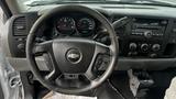 The interior of a 2013 Chevrolet Silverado 1500 featuring a steering wheel with controls a dashboard with gauges and a stereo system