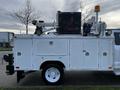 A 2018 Ford F-550 utility truck with a white service body featuring various equipment compartments and a mounted crane on top