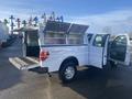 A white 2013 Ford F-150 with its truck bed open and side doors ajar showcasing a spacious cargo area and tool storage compartments