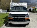 Front view of a white 2013 Chevrolet Express with a black trim and chrome grille parked on a street