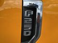A metallic emblem reading F-250 on a bright orange panel of a 2017 Ford F-250 Super Duty truck