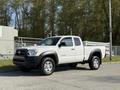 A 2015 Toyota Tacoma in white with a black grille and silver wheels parked on a paved surface
