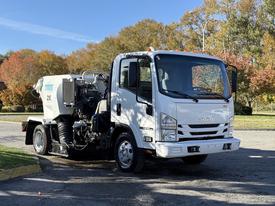 A 2016 Isuzu NPR truck with a white cab and a mounted equipment unit in the rear designed for utility work