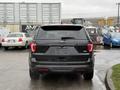 A black 2019 Ford Explorer seen from the rear with a blank license plate and wet surface from rain