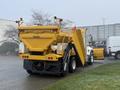 A yellow 2016 International 7400 truck designed for snow plowing with a large hopper at the back and a plow attached at the front