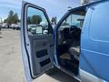 A blue 2009 Ford Econoline van with the driver's side door open displaying the interior and dashboard