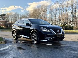 A black 2021 Nissan Murano parked on a wet surface showcasing its sleek design and modern features