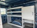 Interior of a 2009 Ford Econoline van featuring metal shelving units and a cabinet against the back wall