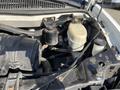 Close-up of the engine compartment of a 2014 Chevrolet Express showing various components including a black air filter housing and a white brake fluid reservoir