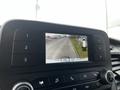 Display screen of a 2020 Ford Transit showing a rearview camera view of a road alongside a curb