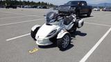 A 2013 Can-Am Spyder four-wheeled motorcycle with a sleek white body and distinctive front design parked in a lot