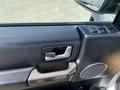 Interior door handle and controls of a 2006 Land Rover LR3 with a black and brown color scheme