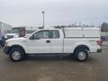 A white 2013 Ford F-150 pickup truck with a cap on the bed and a four-wheel drive emblem on the side