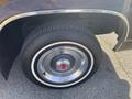 The tire and rim of a 1982 Mercury Grand Marquis showing a chrome hubcap and distinctive tire tread design