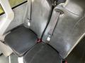 Two black vinyl seats with seatbelts in a vehicle interior