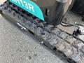 A green 2024 AGT Industrial QH13R Mini Excavator showing a close-up of its tread and tracks