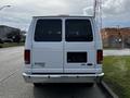 A white 2014 Ford Econoline van is facing the camera with its rear view visible showcasing a blank license plate area