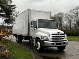 A white 2020 Hino 338 truck with a boxy cargo area and chrome grille parked on a road