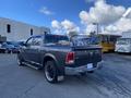 A gray 2017 RAM 1500 pickup truck with custom wheels parked at an angle showing its rear and side profile