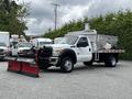 A 2011 Ford F-550 truck equipped with a snow plow attached to the front and a salt spreader in the truck bed
