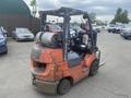A 2010 Toyota 7FGGU25 forklift with an orange body and a propane tank mounted on the rear seat area