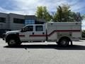 A 2009 Ford F-550 emergency vehicle with a white body and red stripes equipped with a utility box and features large wheels and cab for multiple passengers