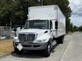 A 2019 International 4300 box truck with a white cargo area and a silver front, featuring a prominent horizontal grille and orange marker lights on top