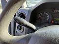 The image shows the steering wheel and control lever of a 2012 Ford Econoline E-450 with gauges visible in the background