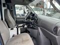 Interior view of a 2006 Ford Econoline showing two front seats a steering wheel and a central console with beverage holders