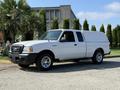 A white 2009 Ford Ranger pickup truck with a cap on the bed and chrome wheels parked on a driveway
