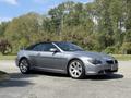 A silver 2004 BMW 6-Series convertible with a black soft top parked at an angle showcasing its sleek design and alloy wheels