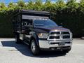 A 2015 RAM 5500 truck with a black dump bed and chrome accents parked in a clear area