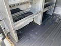 Interior view of a 2013 Ford Transit Connect showing metal shelving units mounted on the left side of the cargo area with a clean but worn rubber floor mat