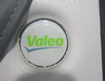 A round Valeo logo sticker on a textured surface in a vehicle interior