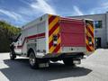 A 2009 Ford F-550 service truck with a white body featuring red and yellow reflective striping and a red roll-up door at the rear