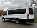 A 2021 Ford Transit white van with black detailing and large windows on the side parked at an angle showcasing its rear and side view