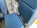 A blue seat of a 2014 Chevrolet Express partially folded up with a storage compartment visible nearby