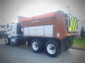 A 2016 International WorkStar 7500 truck with a brown dump bed and a yellow and black striped safety signal on the back