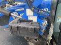 A black storage box mounted on the side of a blue New Holland T475 tractor with a PowerStar logo and warning labels visible