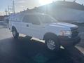 A 2013 Ford F-150 in white with a utility cap on the truck bed and a standard cab design