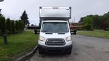 A white 2018 Ford Transit van with a high roof and large cargo area is parked with its front facing towards the viewer