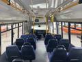 Interior view of a 2018 Chevrolet Express bus showing rows of blue seats and the driver's area with dashboard controls