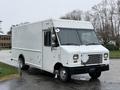 A white 2012 Ford Econoline delivery truck with a boxy shape and large windshield parked on a wet surface featuring a simple design and side and front windows