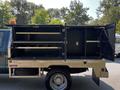A 2008 Ford F-550 with an open storage compartment on the back featuring multiple shelves and a metallic finish