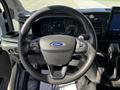 Steering wheel of a 2022 Ford Transit featuring controls for audio and cruise settings with Ford logo in the center