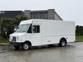 A white 2012 Ford Econoline with a boxy shape and large windshield parked at an angle showcasing its delivery vehicle design and side door