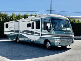 A 2000 Ford Motorhome with a light green and white exterior featuring a slide-out section and large windows